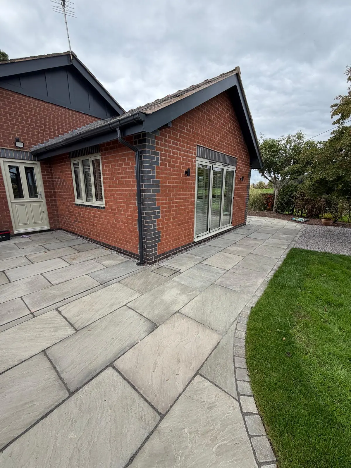 Brick extension with glazed doors and stone paving beside the garden