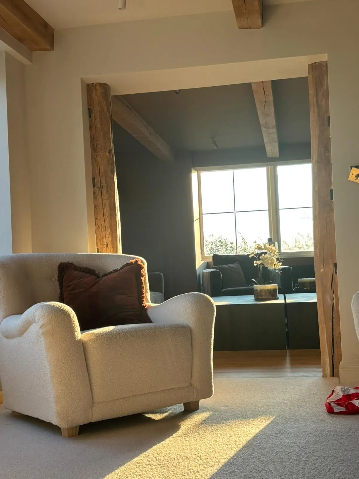 Finished living space with exposed timber beams and a wide opening between rooms