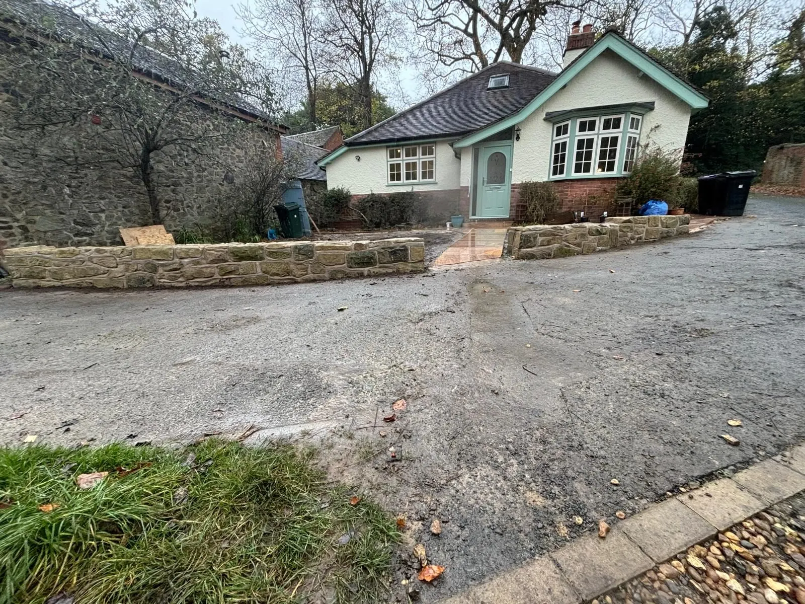 Low stone garden walls framing a cottage entrance and driveway