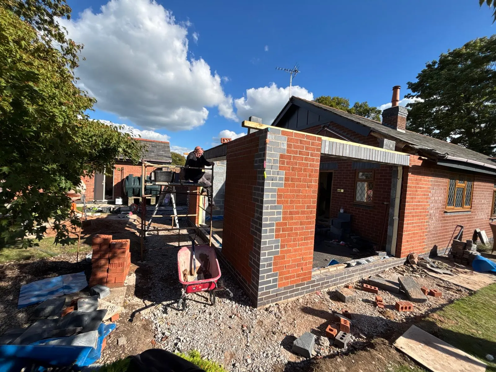 Brick extension shell surrounded by scaffold and stored materials