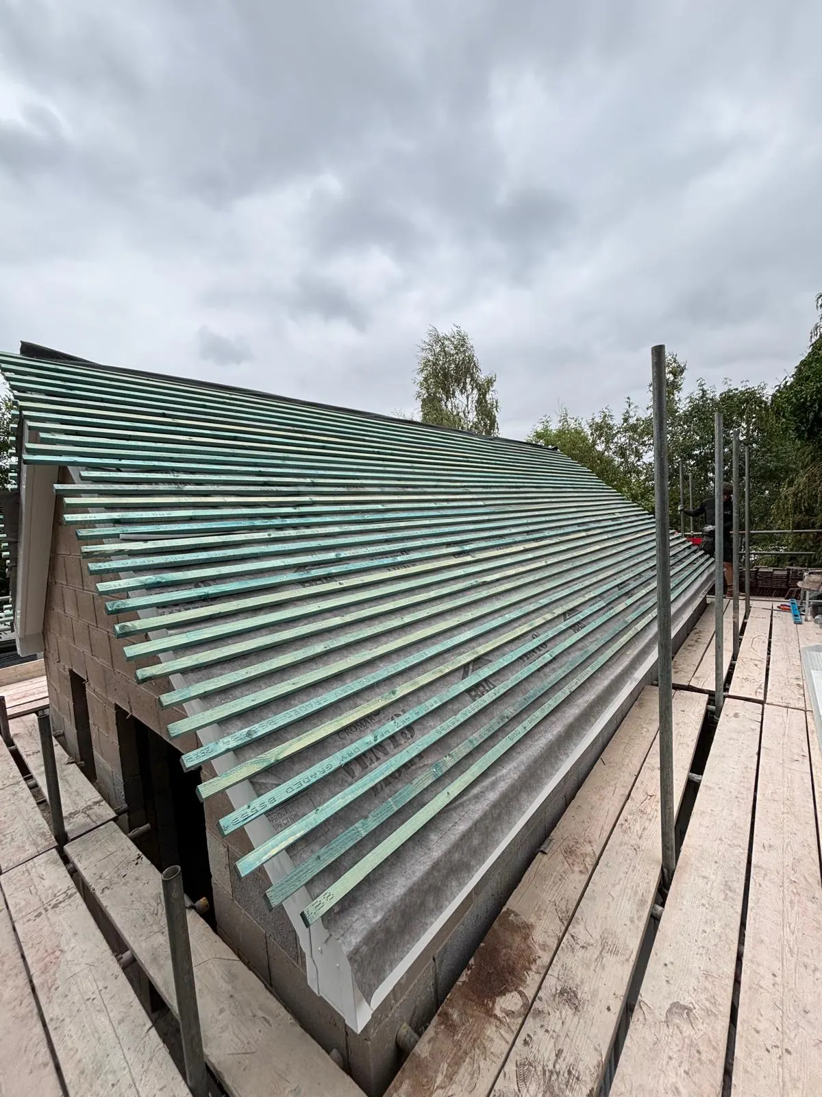 Roof battens installed above a masonry gable beside scaffolding