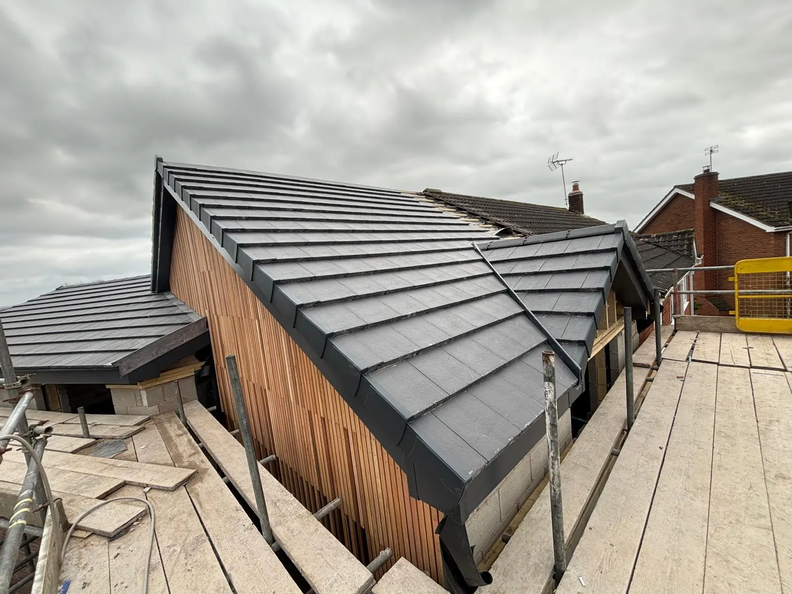 Completed extension with standing-seam roof and timber-clad gable